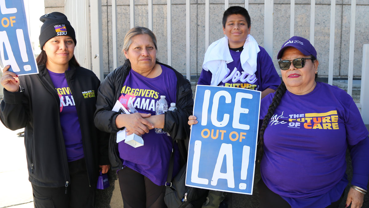 Members holding signs that read "ICE out of LA attend International Migrants Day march in Los Angeles.